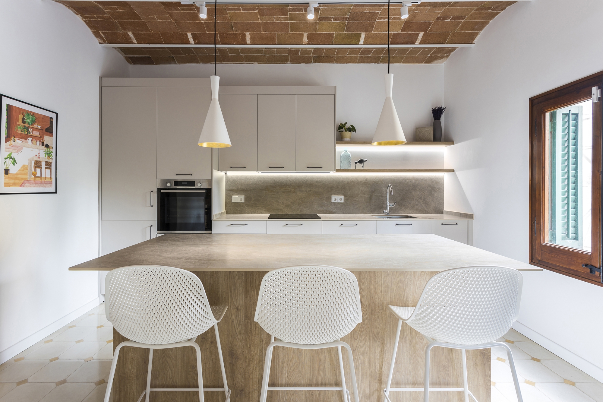 Cocina reformada por Sanisans con techo de bóveda catalana restaurada, isla central y taburetes blancos